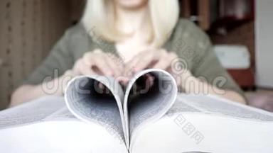 模糊不可辨认的金发女人折叠书页成心形，爱阅读的概念